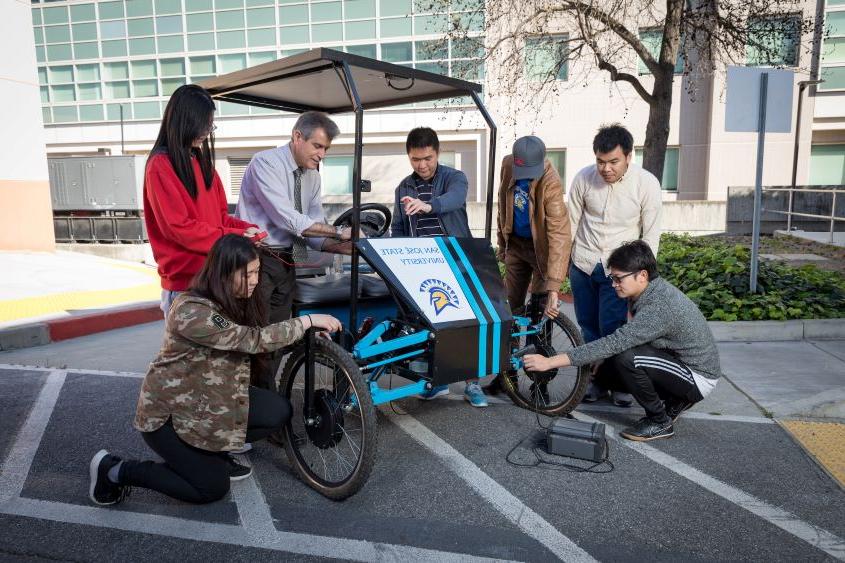 Faculty mentor and students working on a solar-powered bicycle.